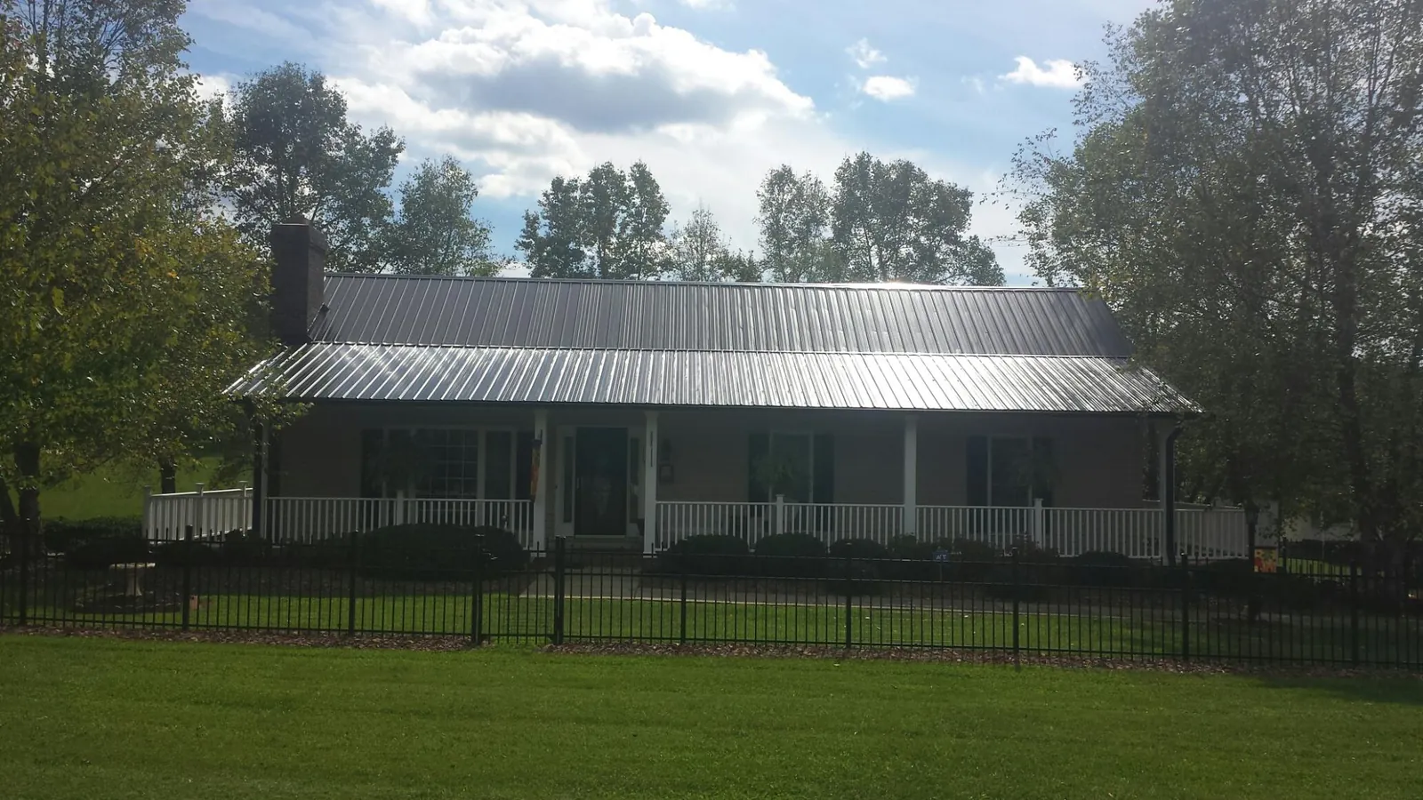Gray metal roof on a brick ranch with a full width front porch — Gutter Guard Installation work by our crew in Maricopa